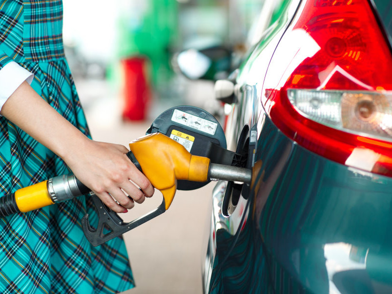 Woman fills petrol into her car at a gas station closeup